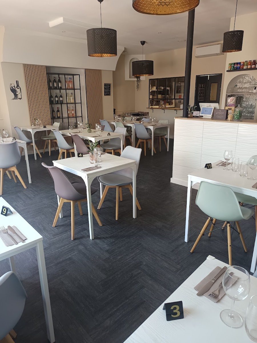 La salle du restaurant : tables blanches, chaises claires, étagère à vins