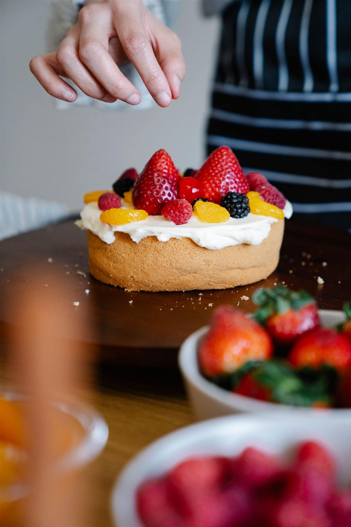 Mains qui terminent une tarte aux fraises et fruits rouges (photo d’illustration)